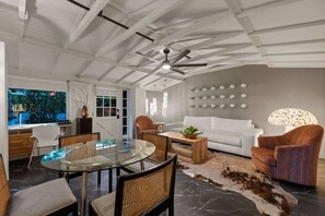 A modern living room with a glass dining table, a white sofa, and a patterned armchair. - Exclusive use of the property (All 5 units) (Palm Springs)