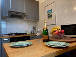 A kitchen with a wooden countertop, a bottle of champagne, two wine glasses, and a bowl of fruit. - Stylish comfortable apartment (Prague 2)