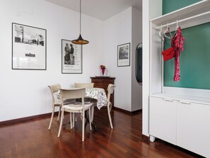 Uma área de refeições com mesa posta para quatro pessoas, uma luminária pendente e quadros nas paredes.