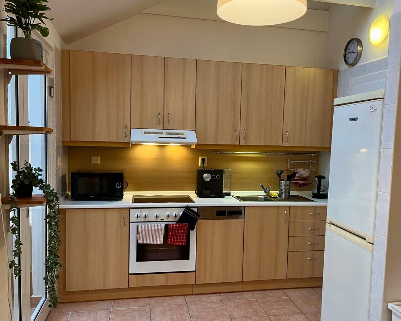 Een compacte keuken met houten kastjes, een magnetron, een koffiezetapparaat en een inbouwoven.