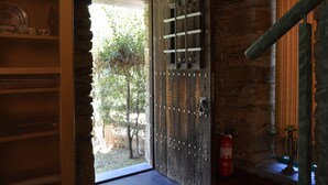 Una puerta de madera rústica con refuerzos de metal, un extintor de incendios en la pared y un muro de piedra.