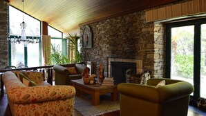 Un salón acogedor con chimenea de piedra, techo de madera y un ventanal grande.