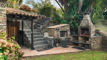 Ein rustikales Steinhaus mit Holztür und kleinem Steinofen.