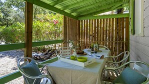 A covered patio with a table set for two, surrounded by metal chairs with cushions.