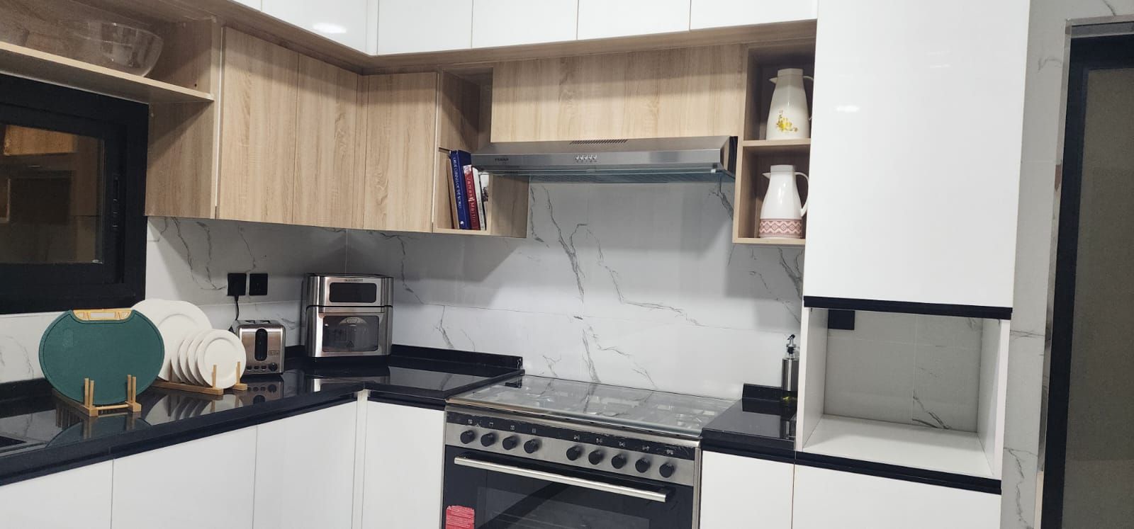 A kitchen with white cabinets, a stove, a toaster, and a microwave.