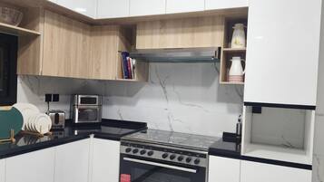 A kitchen with white cabinets, a stove, a toaster, and a microwave.