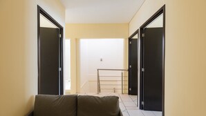 A narrow hallway with a sofa, two doors, and a metal railing. - Casa Chiapas | Stay in the Heart of the City (Puebla)