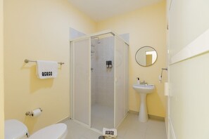 Une salle de bain comprenant des toilettes, un lavabo, un espace douche et un miroir.