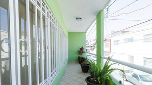 A balcony with potted plants, a railing, and a view of the street. - Casa Chiapas | Stay in the Heart of the City (Puebla)