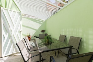 A glass-top table with four chairs, a potted plant, and a white lattice structure. - Casa Chiapas | Stay in the Heart of the City (Puebla)