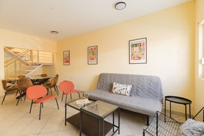 A living room with a grey sofa, red chairs, a glass coffee table, and a staircase in the background. - Casa Chiapas | Stay in the Heart of the City (Puebla)