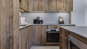 A modern kitchen with wooden cabinetry, a built-in oven, and a coffee maker. - Stunning High-End Apartment with balcons, Les Rives de l’Isère 3 (Val-d'Isère)