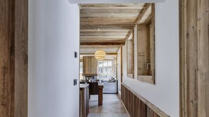 A hallway with wooden paneling, a dining area with a table and chairs, and a hanging light fixture. - Stunning High-End Apartment with balcons, Les Rives de l’Isère 3 (Val-d'Isère)