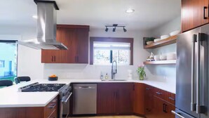 A modern kitchen with wooden cabinets, stainless steel appliances, and a window providing natural light. - Stylish Mid-Century Modern Home - Near DT Portland for your perfect getaway! (Milwaukie)