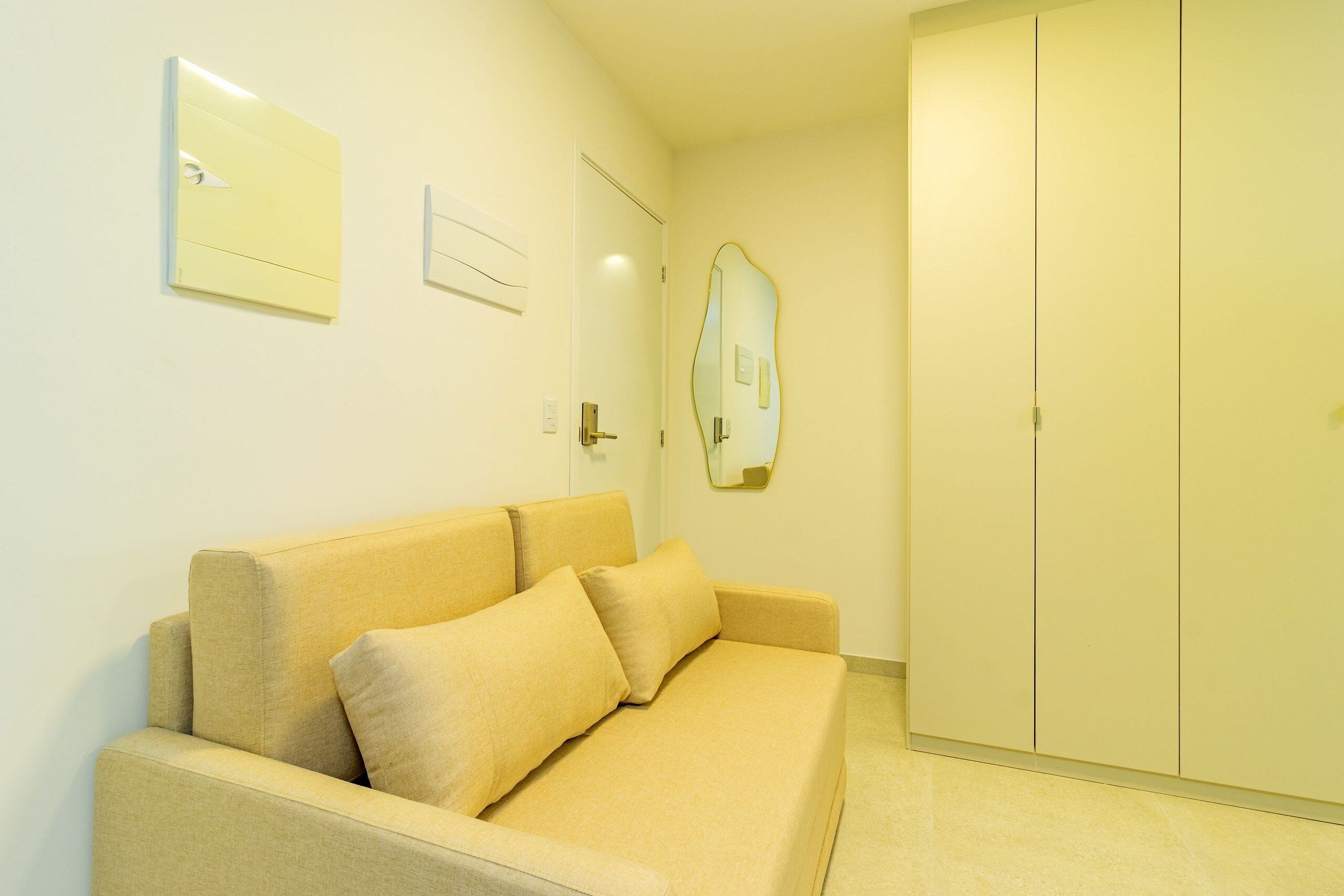 A neutral-colored room with a beige sofa, a door, and a wardrobe.