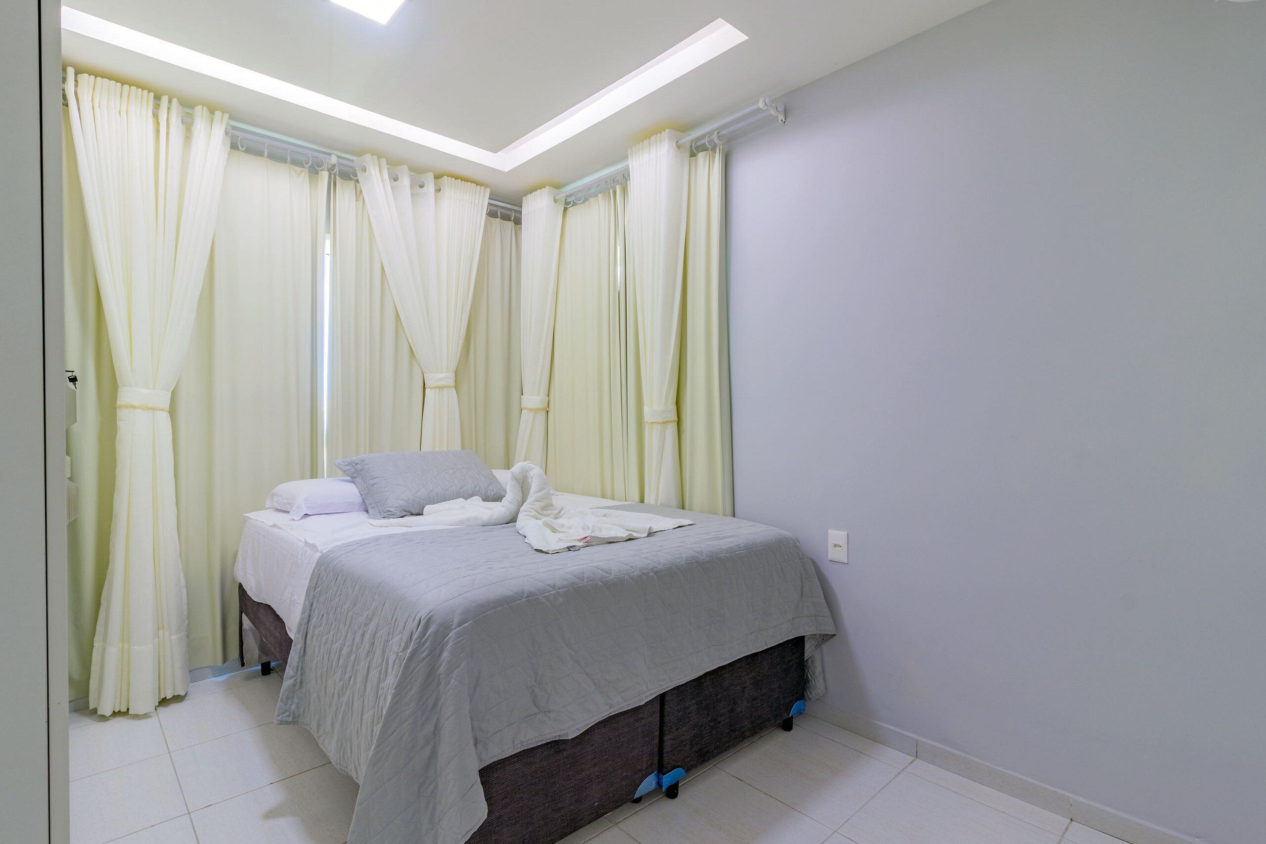 A bedroom with a bed, curtains, and a ceiling light.