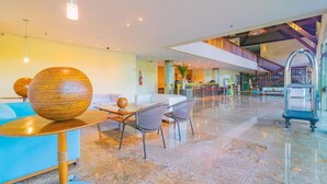A modern lobby with a reception desk, seating area, and a staircase leading to upper floors. - Marulhos Suites Resort - Triplo By Carpediem (Ipojuca)