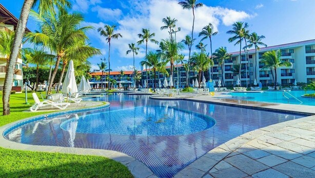 A resort pool area with multiple swimming pools, palm trees, and lounge chairs. - Marulhos Suites Resort - Triplo By Carpediem (Ipojuca)