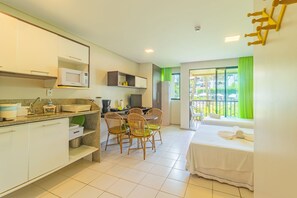 Quarto de hotel com cozinha compacta, espaço de jantar e uma cama.