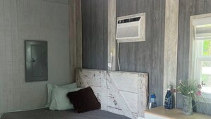 Un dormitorio con una cama, un armario blanco, un ventilador de techo y una ventana.