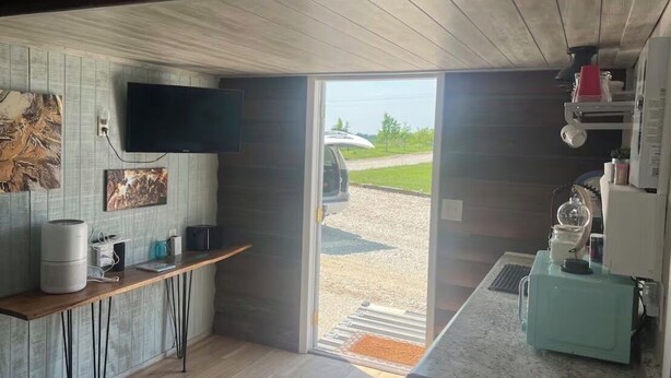 Una cocina moderna con televisor de pantalla plana, una mesa de madera y un ventanal grande.