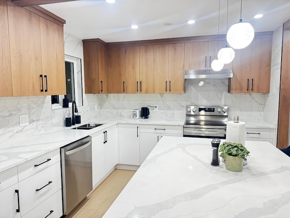 A modern kitchen with wooden cabinets, white countertops, a built-in oven, and a central island with a plant.