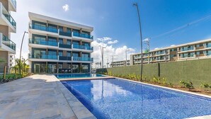 A modern building with a swimming pool, featuring a multi-story structure with balconies and a flat roof. - Makia Beach #c22 - Apto Inteligente by Carpediem (Ipojuca)