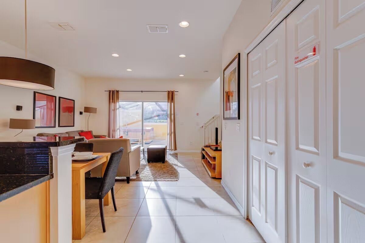 A modern hotel room with a dining area, a sofa, a TV, and a view of the outdoors.