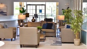 Eine moderne Hotellobby mit einer Sofagruppe, einem Couchtisch und einer großen Topfpflanze.