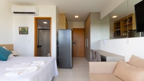 Une chambre d’hôtel équipée d’un lit, d’un canapé, d’un réfrigérateur, d’une armoire en bois et d’un téléviseur.