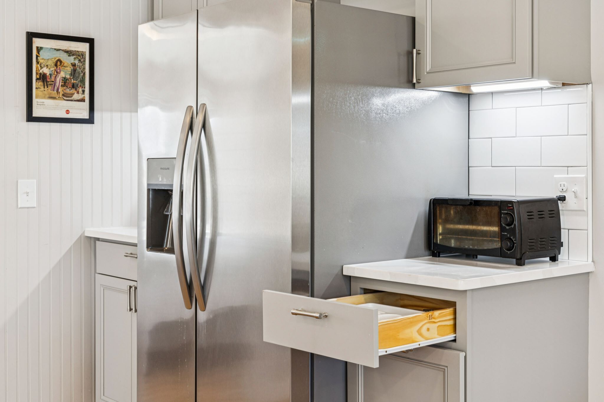 A kitchen with a stainless steel refrigerator, a microwave, and a drawer unit.