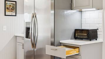 A kitchen with a stainless steel refrigerator, a microwave, and a drawer unit.