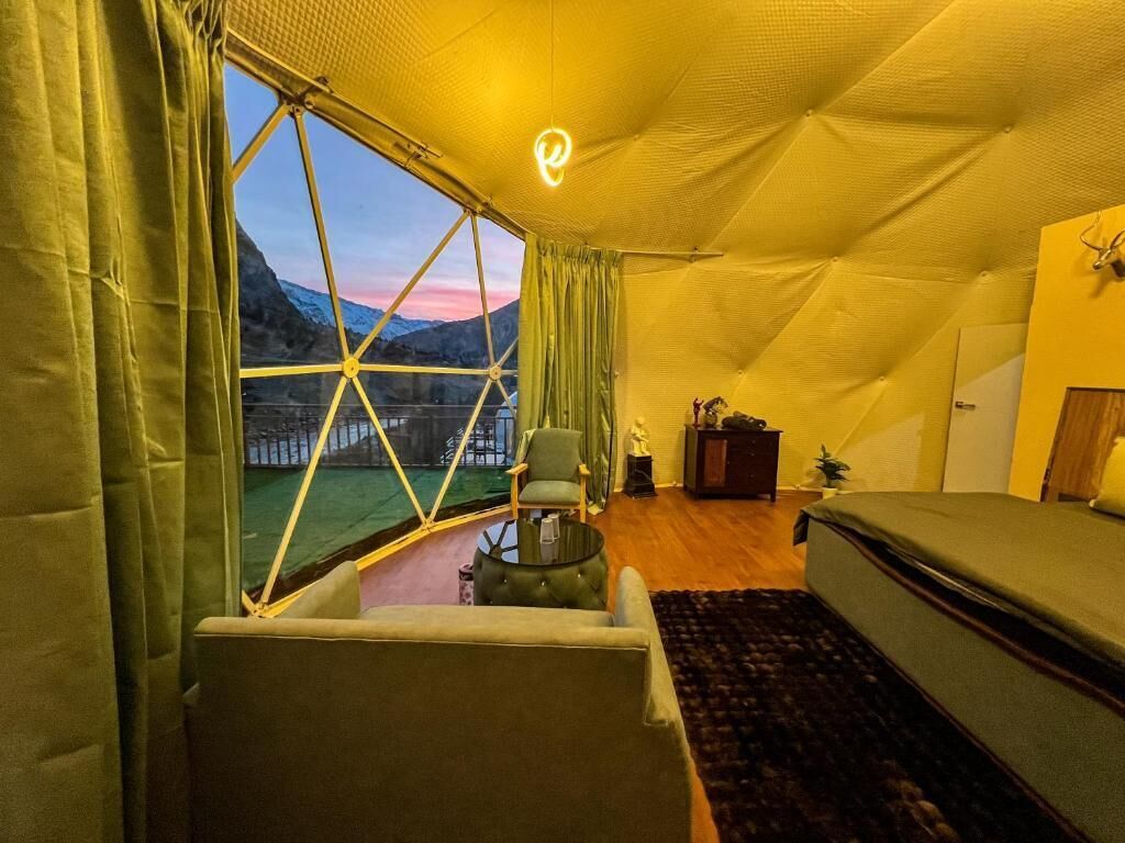 A cozy room with a large window, a bed, a chair, and a small table.