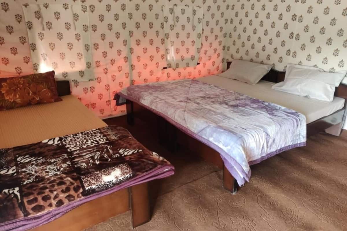 A bedroom with a bed, a bench, and patterned curtains.