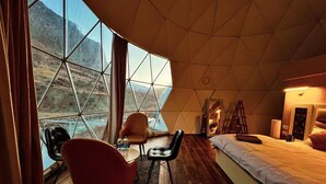 Une pièce avec une grande fenêtre, un lit, un bureau et une chaise.