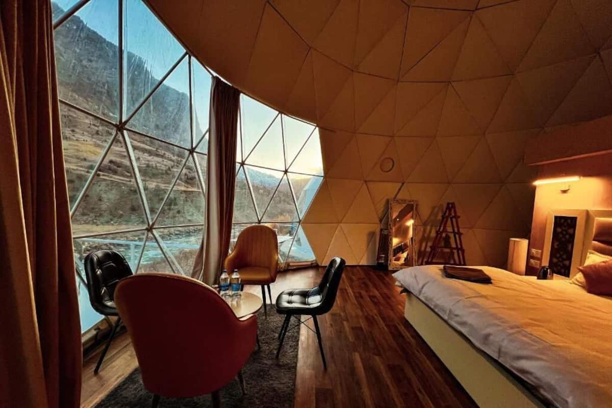 A room with a large window, a bed, a desk, and a chair.