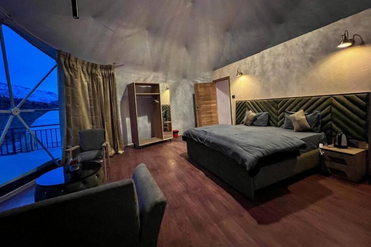 A bedroom with a bed, bedside table, and a window with curtains.