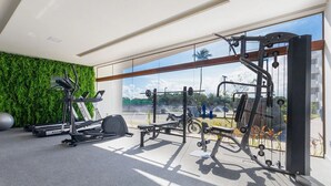 A modern gym with cardio machines, weightlifting equipment, and a green wall. - Makia Beach #D3 - em Muro Alto por Carpediem (Ipojuca)