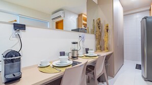 A modern kitchen with a built-in coffee maker, a kettle, and a refrigerator. - Makia Beach #D3 - em Muro Alto por Carpediem (Ipojuca)