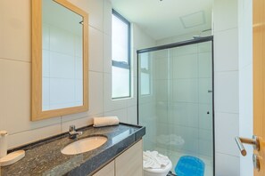 Een badkamer met een marmeren wastafel, een spiegel en een douchecabine van glas.