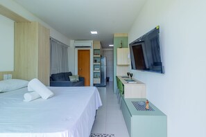 Een hotelkamer met een bed, bureau, televisie en kitchenette.