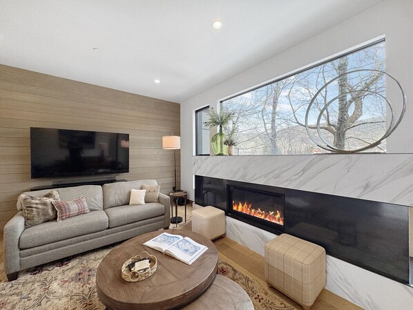 A modern living room with a sofa, coffee table, and fireplace.