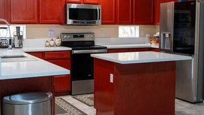A modern kitchen with red cabinets, stainless steel appliances, and a central island.