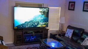 A living room with a television, a sofa, a coffee table, and a ceiling fan.