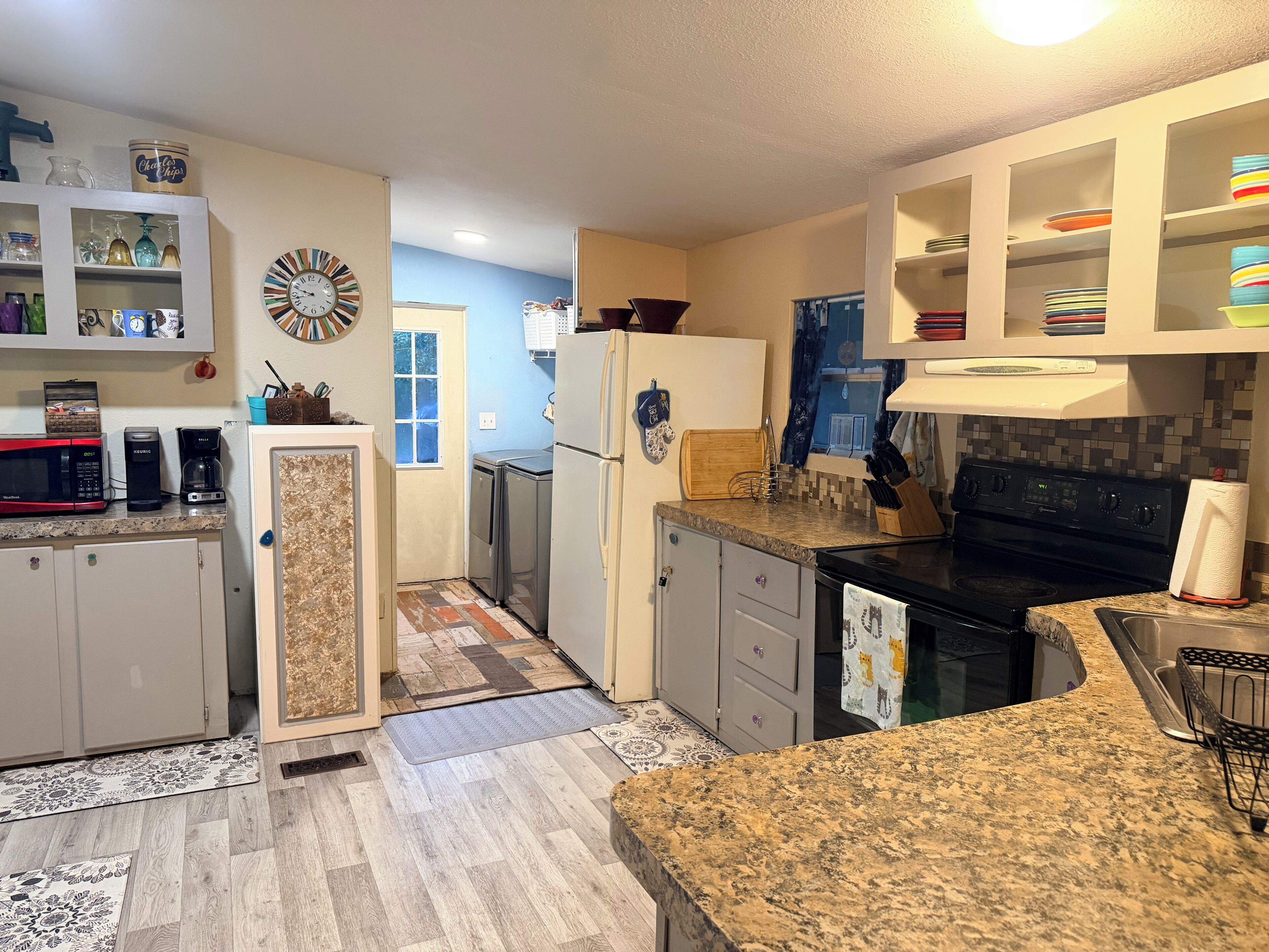 A modern kitchen with granite countertops, stainless steel appliances, and a variety of storage cabinets.