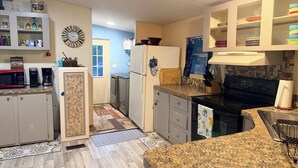 Een moderne keuken met granieten aanrechtbladen, roestvrijstalen apparatuur en diverse opbergkasten.