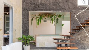 Ein modernes Interieur mit einer Steinwand, einer Holztreppe und einer Sitzecke mit einer Pflanze.