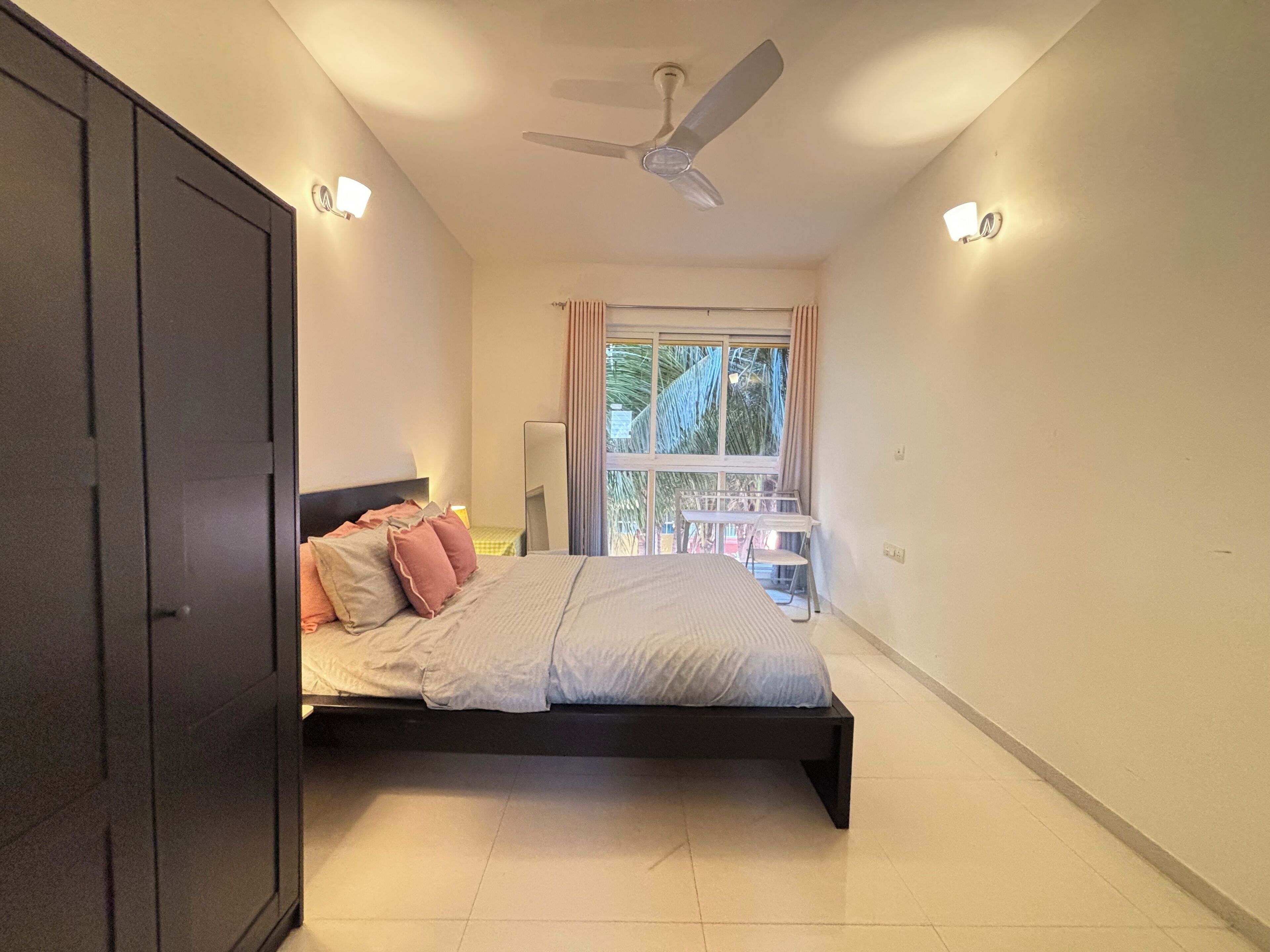 Una camera da letto con un letto, una ventola a soffitto e una finestra con tende.