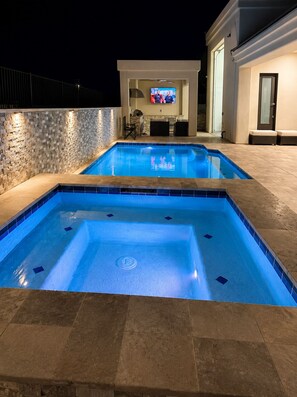 Ein Swimmingpool mit einer Steinwand und einem Fernseher im Hintergrund.