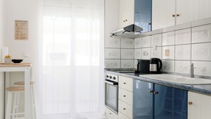 A modern kitchen with white and blue cabinets, a stainless steel stove, and a hanging light fixture.